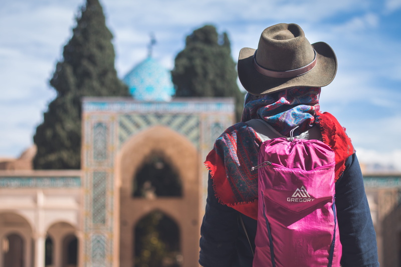 shah nemat-o-llah vali, focus on foreground, human, jacket, person, girl, blue sky, outdoors, hat, carrying, coat, cowboy hat, waist up, one person, dome