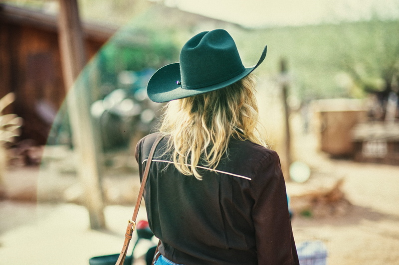 purse, architecture, handbag, women, human, woman, long hair, sun hat, person, clothing, overcoat, blonde, adult, cowgirl, cowboy, waist up, hairstyle