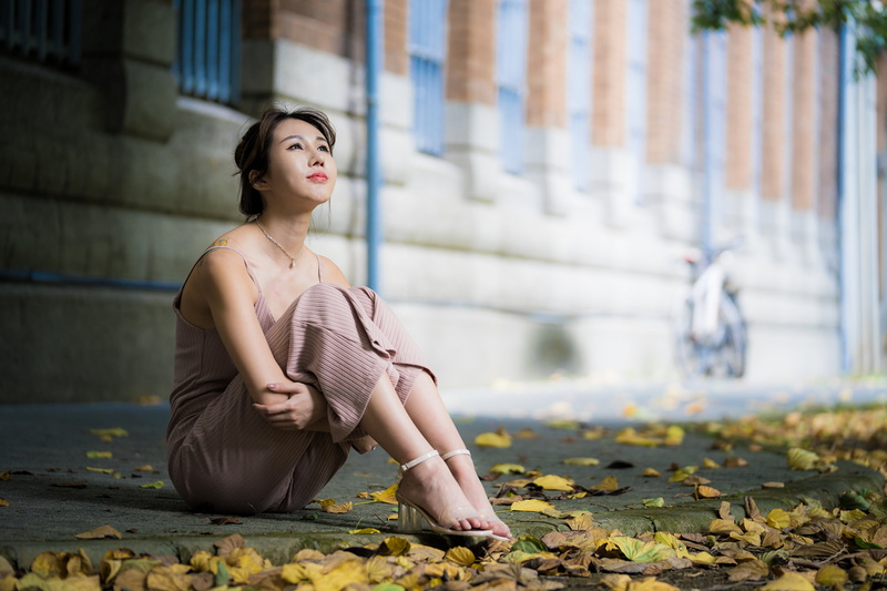 Asian, dark hair, model, pink dress, sitting, necklace, looking up, tattoo, long hair, women outdoors, women, depth of field, barefoot sandal, building