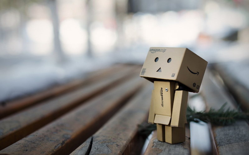 toy, outdoors, no people, depth of field, Danbo, robot, close-up, power, day, gray, focus on foreground, metal, human representation, cardboard, bench