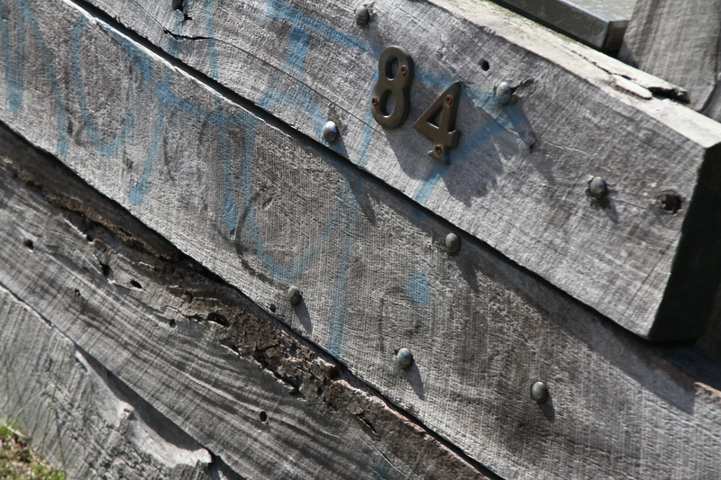 sunlight, still life, fence, wood, day, work tool, high angle view, focus on foreground, metal, rusty, close-up, hand saw, old-fashioned, number 84, old