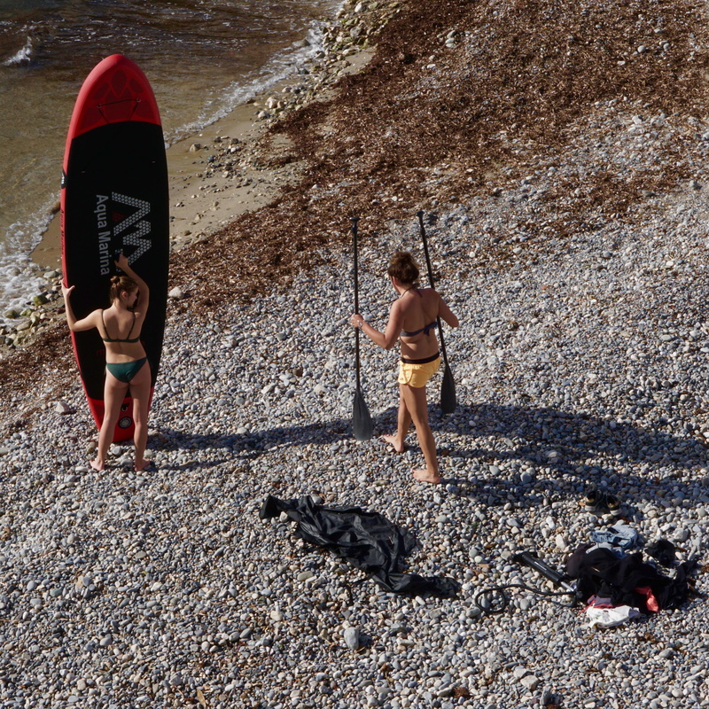 rubble, person, tire, water, sunlight, surfboard, holding, sea waves, pebble, paddle, lifestyles, sea, board, men, land, real people, two people, nature