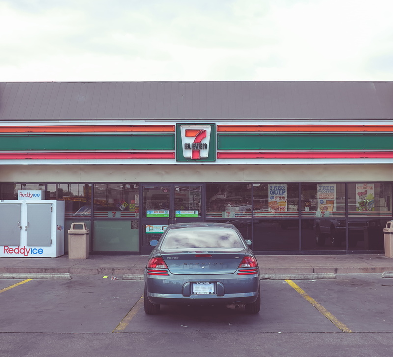 built structure, road, outdoors, motion, transportation, communication, day, convenience store, land vehicle, sign, motor vehicle, mode of transportation
