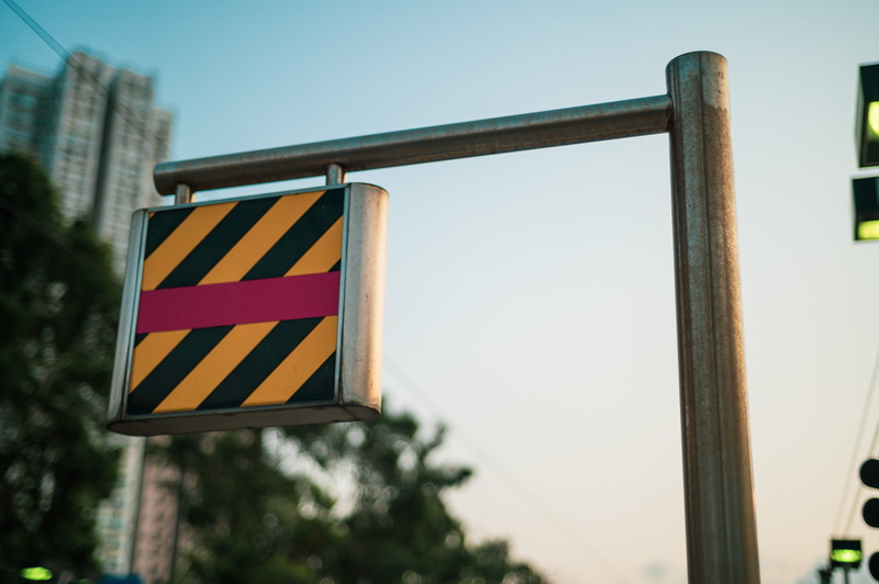 architecture, outdoors, plate, strobes, tarmac, triangle, clear sky, pole, road, building, asphalt, office building, bus stop, symbol, city, arrow, road sign