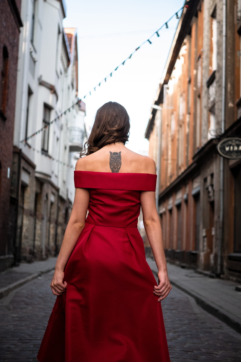 tattoo, pose, hairstyle, shoulder, day, sky, panasonic, architecture, walk, dress, facing, solitude, city, female, red, outdoors, built structure, alone