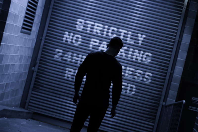 technology, tattoo, one person, standing, holding a camera, pedestrian, roller, sign, 4K, home decor, moody, silhouette, man walking, man in dark, western script