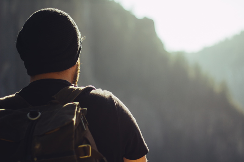 casual clothing, outdoors, hiking, waist up, adventure, headshot, one person, backpack, rear view, warm clothing, day, mountains, focus on foreground, men