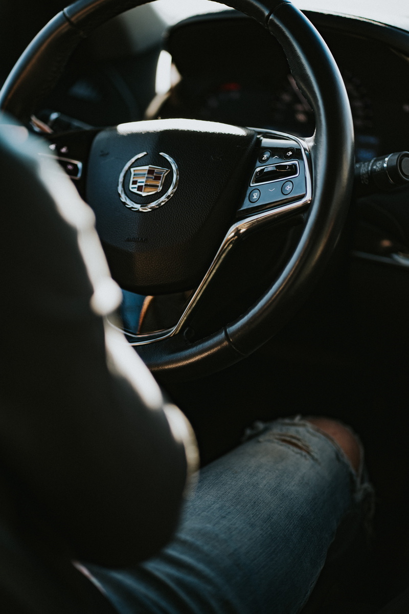 symbol, distressed, clothing, denim, hand, gauge, cadillac, gearshift, human leg, car interior, vehicle interior, crowd, road trip, steering wheel, human body part