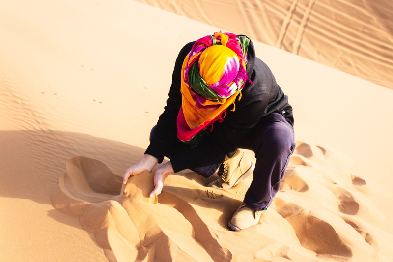 lifestyles, innocence, one person, sitting, helmet, females, childhood, hill, blue, dunes, full length, sunlight, leisure activity, clothing, human, apparel