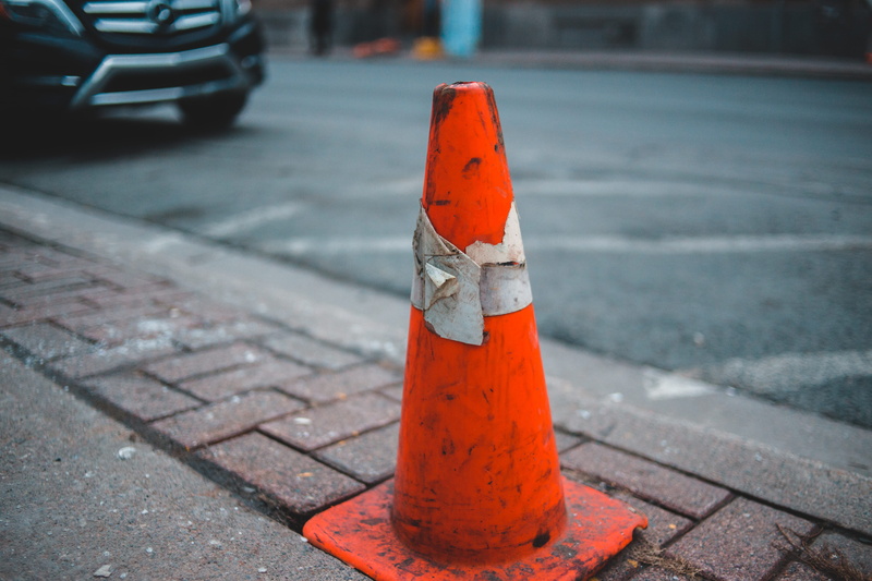 vehicle, traffic cone, footpath, car, day, focus on foreground, alloy wheel, automobile, street, transportation, safety, tarmac, road, close-up, wheel