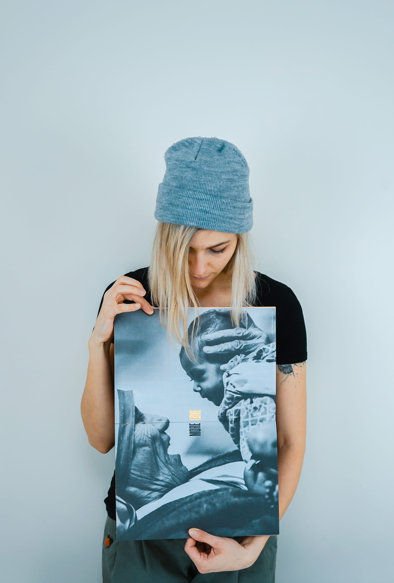 one person, daughter, young adult, black, woman, beanie, holding, 4K, waist up, blue background, female, front view, top, women, indoors, blond hair, hat