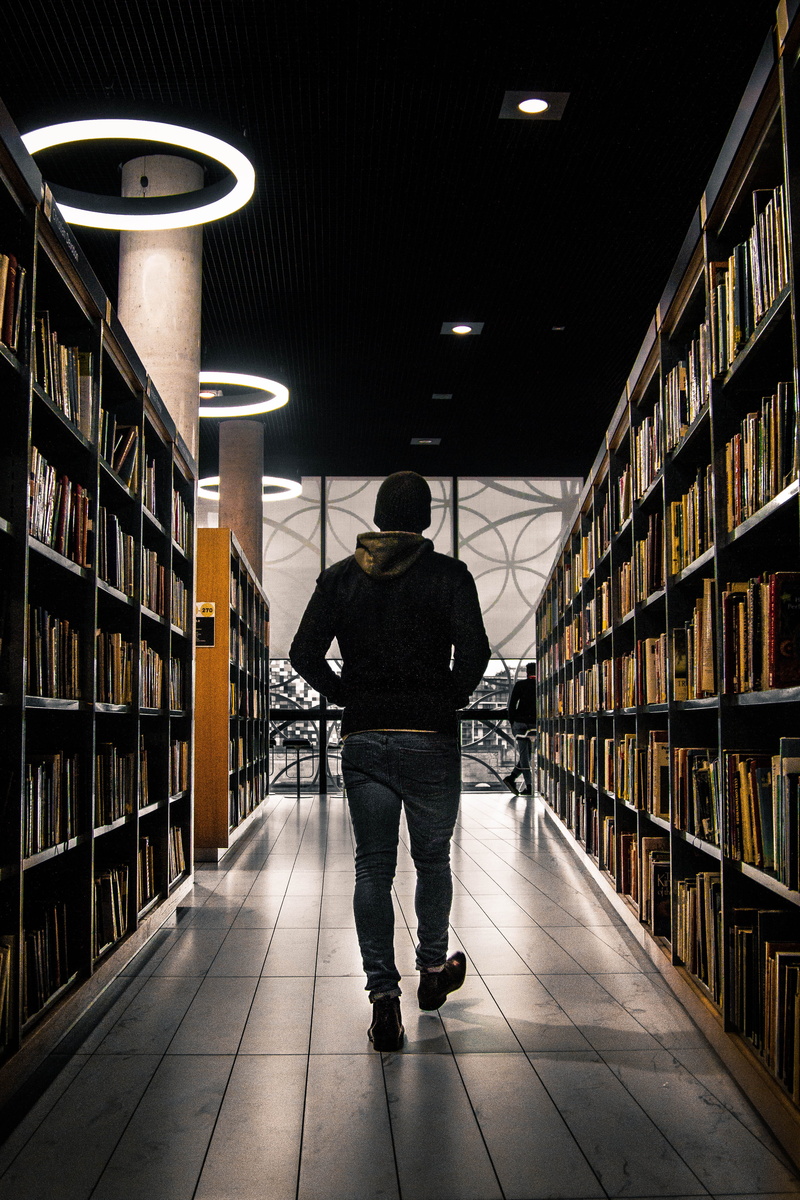 education, one person, studying, lighting equipment, library, large group of objects, united kingdom, mood, bookshelf, walking, architecture, research