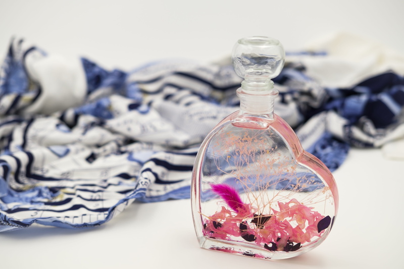 large group of objects, perfume, nature, container, no people, close-up, luxury, focus on foreground, flavors, still life, table, beauty, heart, 5K, textile