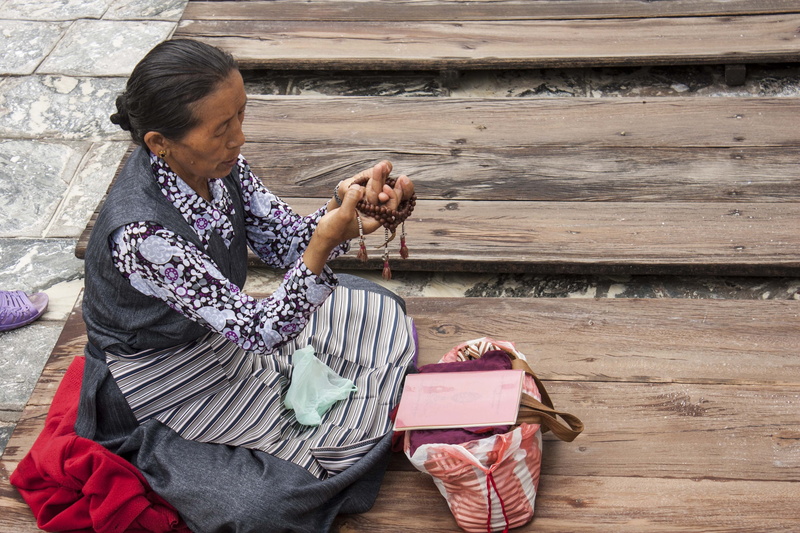 real people, wooden, buddhist, outdoors, casual clothing, cultures, vertebrate, dog, holding, beads, rolling, one person, pets, woman, lifestyles, buddist temple