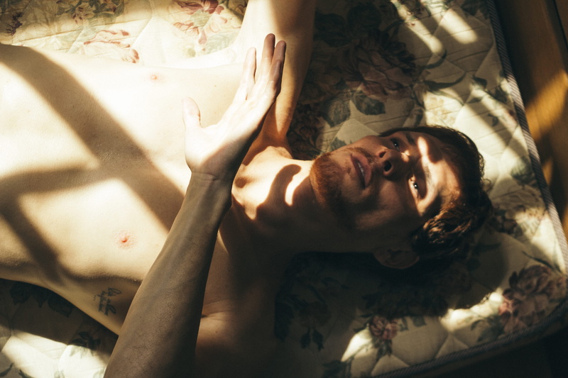 one person, hand, facial hair, lying down, leisure activity, high angle view, indoors, looking at camera, relaxation, photoshoot, man, guy, person, eyes closed