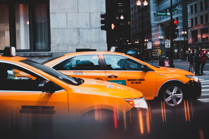 photo, street, two, outdoors, transportation system, pavement, traffic, yellow taxi, action, automobiles, built structure, vehicles, motor vehicle, land vehicle