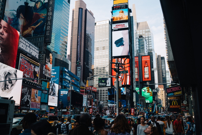 office building exterior, building exterior, new york city, billboard, crowd, modern, density, large group of people, group of people, advertisement, commercial sign