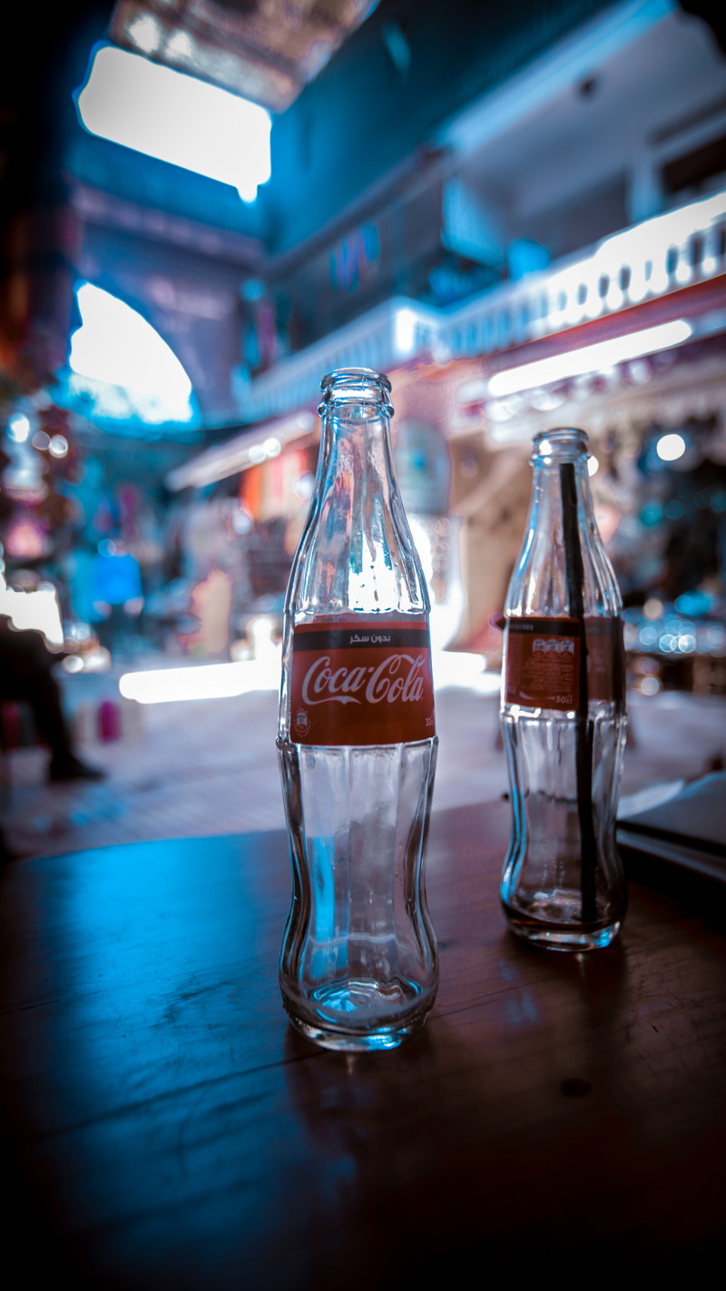 beverage, bottle, alcohol, soda, person, glass, still life, two, glass - material, business, no people, blue, room, cocacola, close-up, focus on foreground