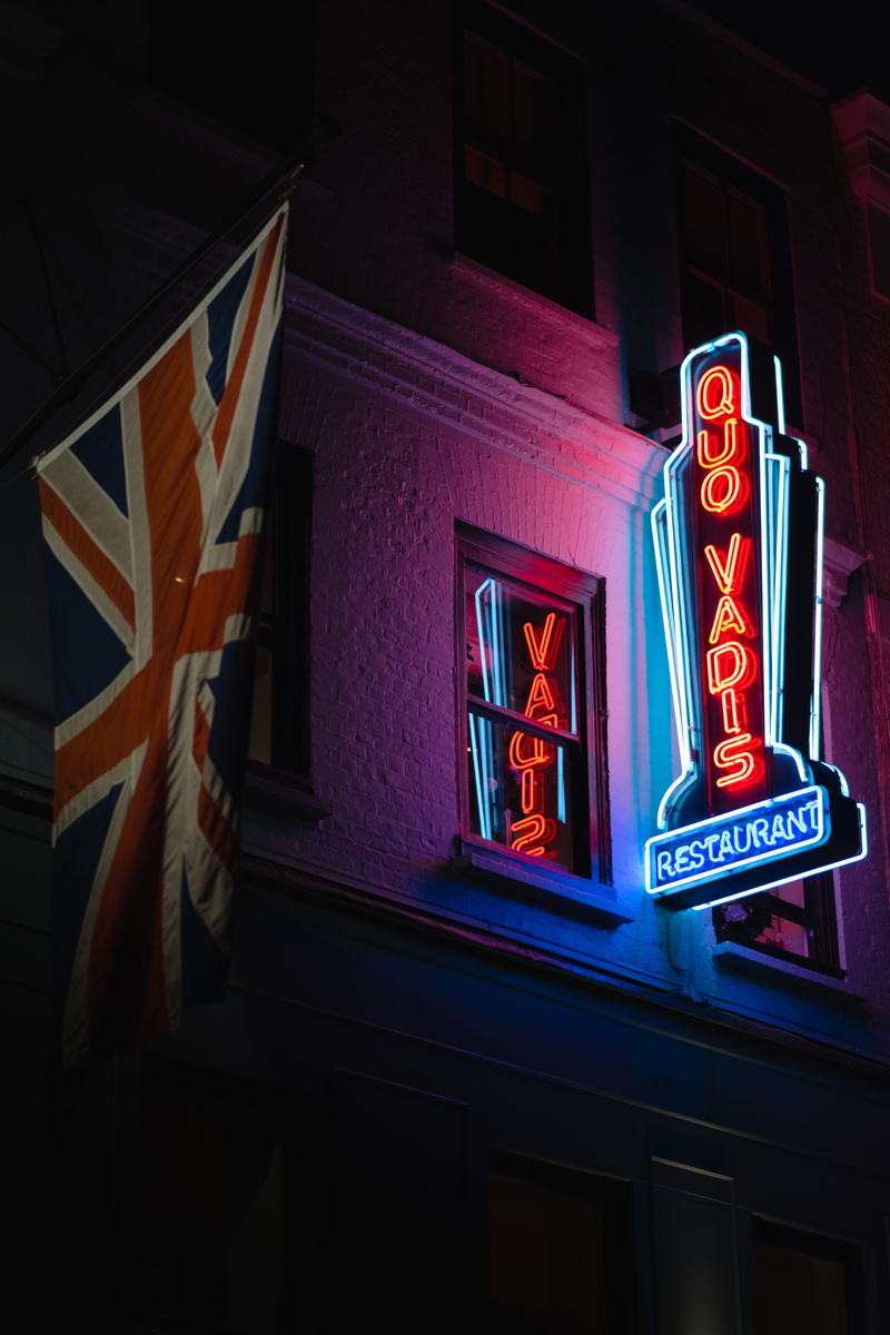city, commercial sign, restaurant, human representation, illuminated, capital letter, red, british flag, dark, view, low, drink, building exterior, vadis