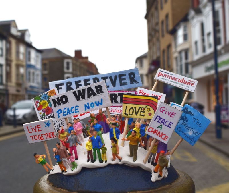 focus on foreground, information, march, non-western script, outdoors, give peace a chance, wales, little people, toy, sweet food, anti, colourful, built structure