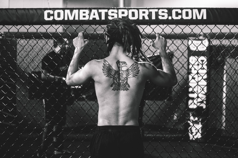 leisure activity, fence, men, martial Arts, text, chainlink fence, shirtless, fighter, western script, rear view, boundary, tattoos, real people, mMA, standing