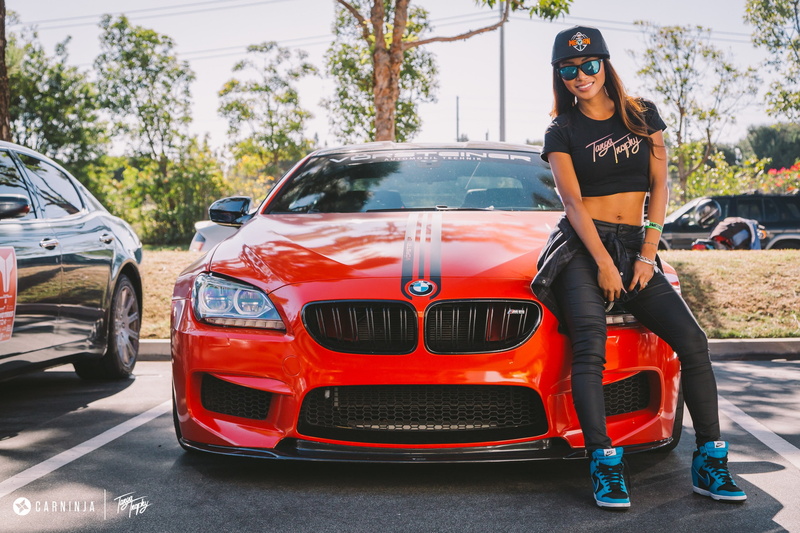 real people, sunglasses, red, motor vehicle, outdoors, BMW M4 Coupe, car, front view, casual clothing, day, land vehicle, low, 2K, young adult, young women