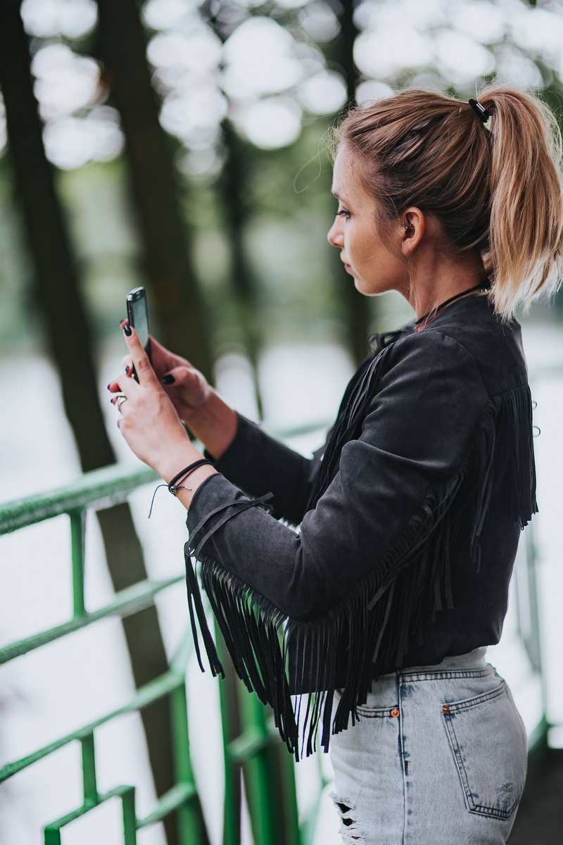 caucasian Ethnicity, ripped, adults only, casual Clothing, Blonde, hairstyle, using phone, female, day, lifestyles, girl, jacket, wireless technology, black