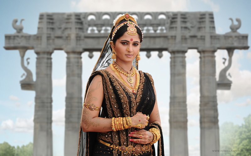 day, traditional clothing, architecture, clothing, looking at camera, built structure, focus on foreground, Anushka, standing, Rudhramadevi, beautiful woman