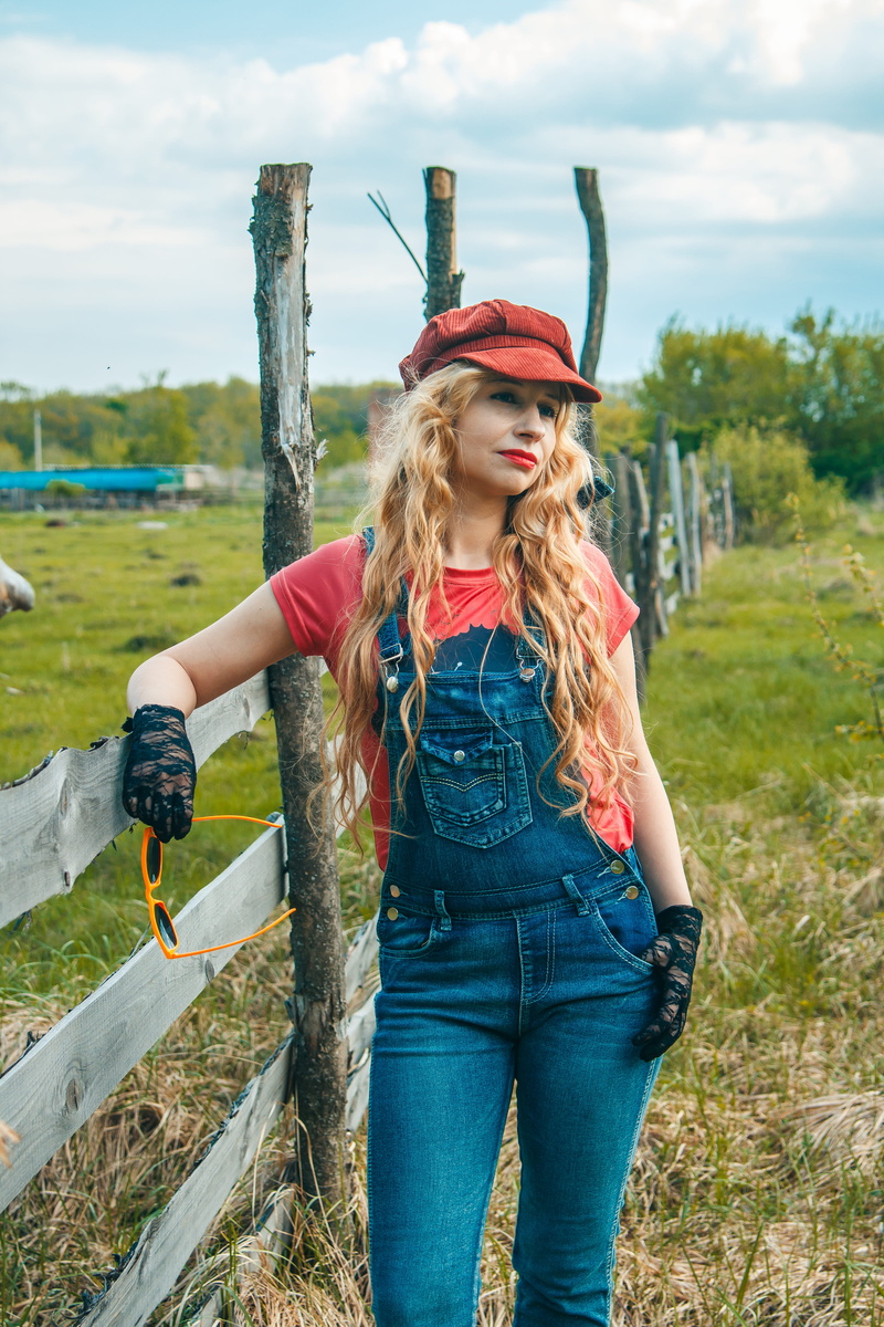 hairstyle, young adult, day, fence, dungarees, casual clothing, one person, hair, nature, real people, focus on foreground, long hair, beautiful woman