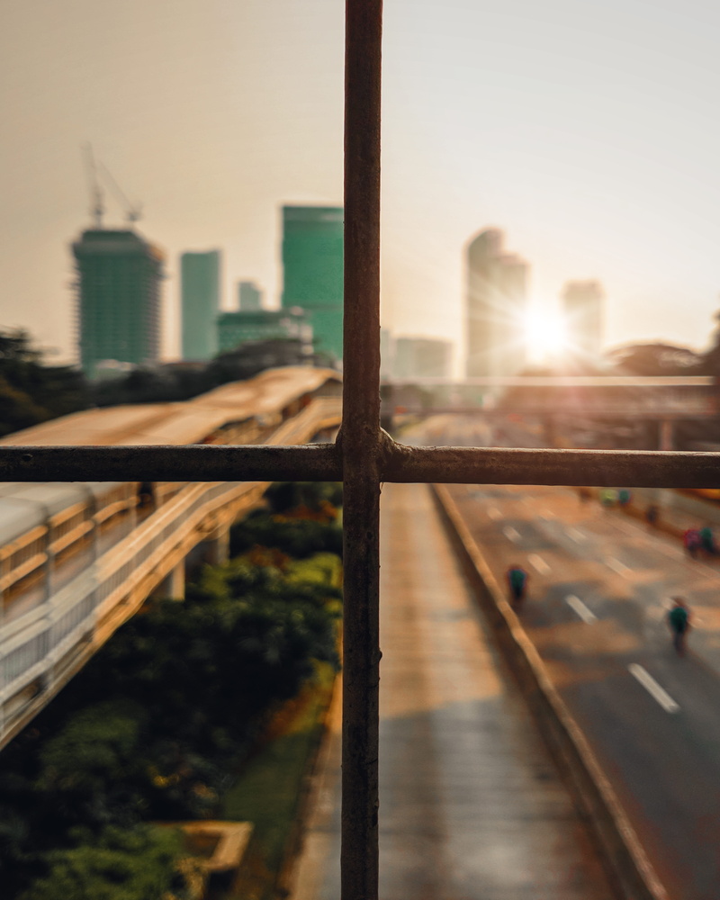 bokeh, building exterior, bar, built structure, sky, transportation, city view, fence, photography, architecture, sun, sunlight, road, outdoors, skyscraper