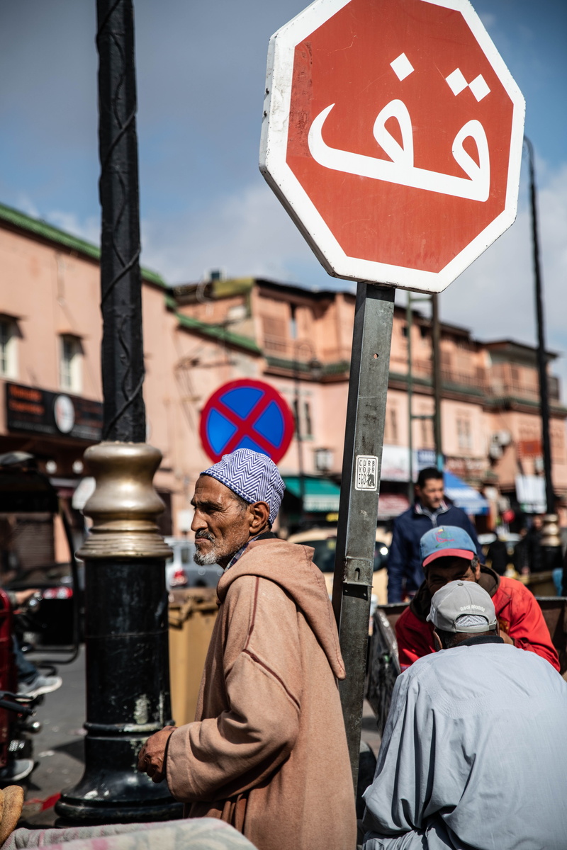 stopsign, men, road, cap, person, turban, focus on foreground, clothing, real people, communication, drink, 8K, built structure, sleeve, hat, day, stop sign