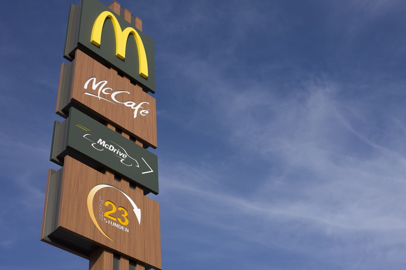 communication, sky, fast food, no people, outdoors, symbol, shield, mcdonalds, low angle view, mccafe, western script, text, arrow symbol, drive in, signage