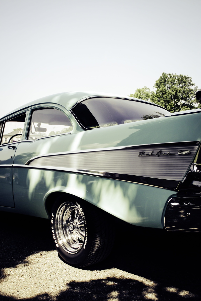 outdoors, rarity, vintage car, day, clear sky, tree, land vehicle, no people, chrome plated, mode of transportation, sunlight, big block, spotlight, wealth