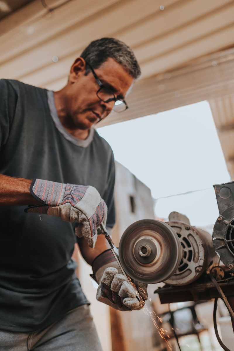 focus on foreground, glasses, work tool, mature men, workshop, casual clothing, accessories, person, art and craft, wristwatch, apparel, grinder, spoke