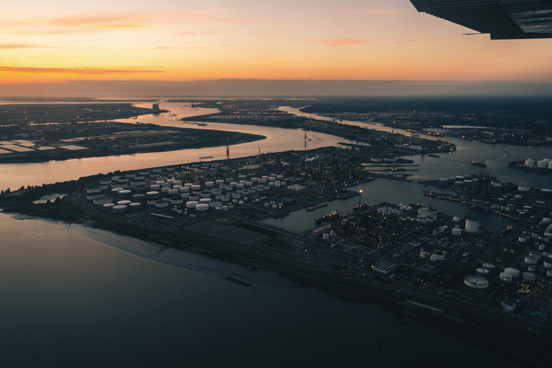 built structure, pilot, outdoors, antwerpen, beauty in nature, travel, sky, sun, city, air vehicle, silos, ocean, reflection, sea, industrial, mode of transportation