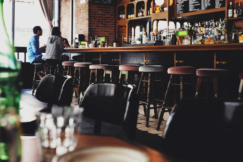 real people, glass, people, indoors, bar counter, chairs, alcohol, two, pub, lifestyles, arrangement, front, desk, 4K, sitting, cafe, nightlife, incidental people