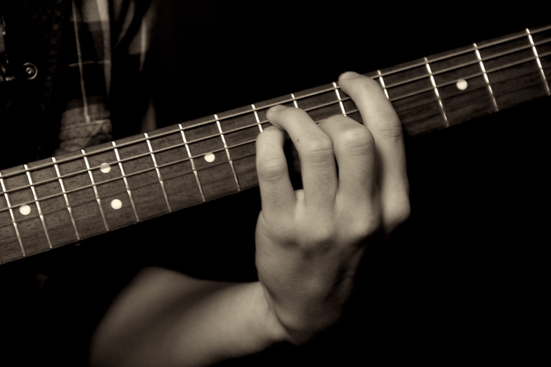 artist, indoors, fretboard, oldschool, plucking an instrument, finger, les paul, one person, musical equipment, human body part, musical instrument, black background