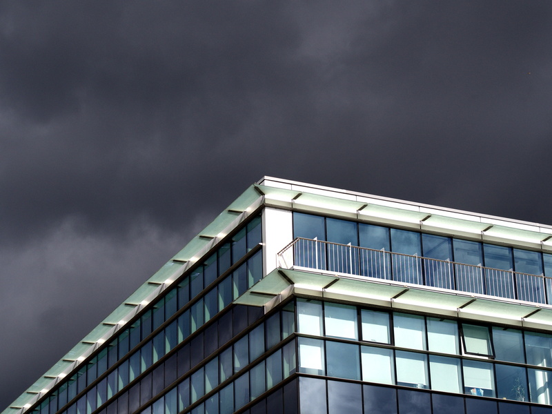 office building exterior, low angle view, gray, windowed, window, clouds, day, city, cloudy, modern, grey, black, glass, overcast, cloud - sky, architecture