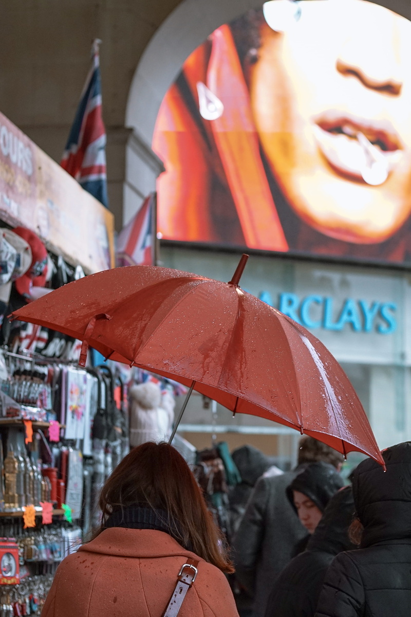 billboard, crowd, raining, wet, street market, group of people, city, holding, leisure activity, market, retail, day, woman, inside, barclays, lifestyles