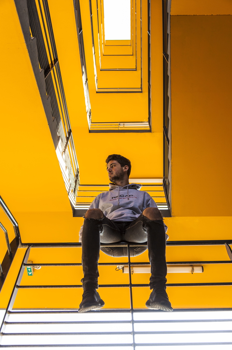 looking up, adult, casual clothing, contemplation, people, men, sadness, full length, seat, front view, furniture, architecture, building, hoodie, railing