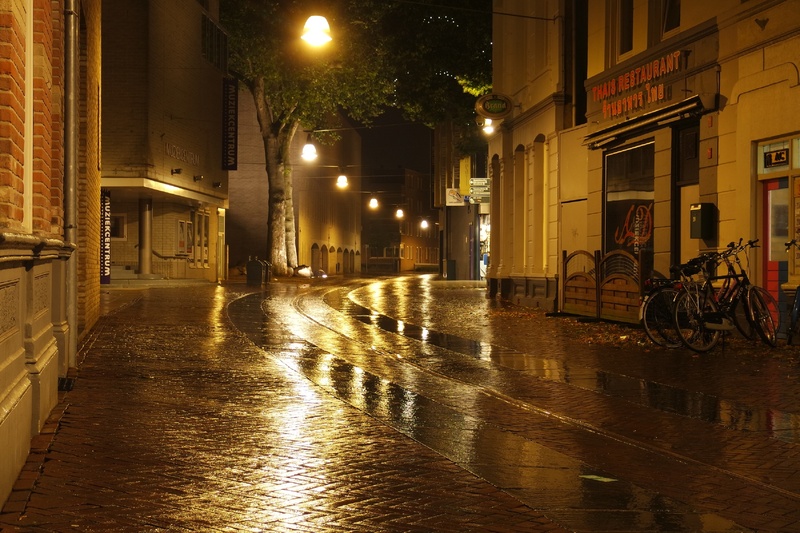 street light, footpath, reflections, no people, rain, buildings, concrete, city, dark, moisture, outdoors, street lamp, building, water, rainy season, sidewalk