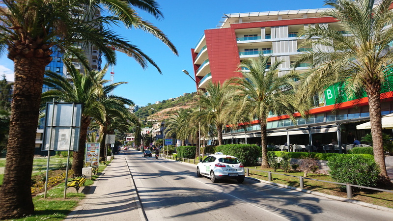 street, palm tree, built structure, tropical climate, city, car, land vehicle, shopping mall, balkans, budva, taxi, tree, sunlight, main street, road, motor vehicle