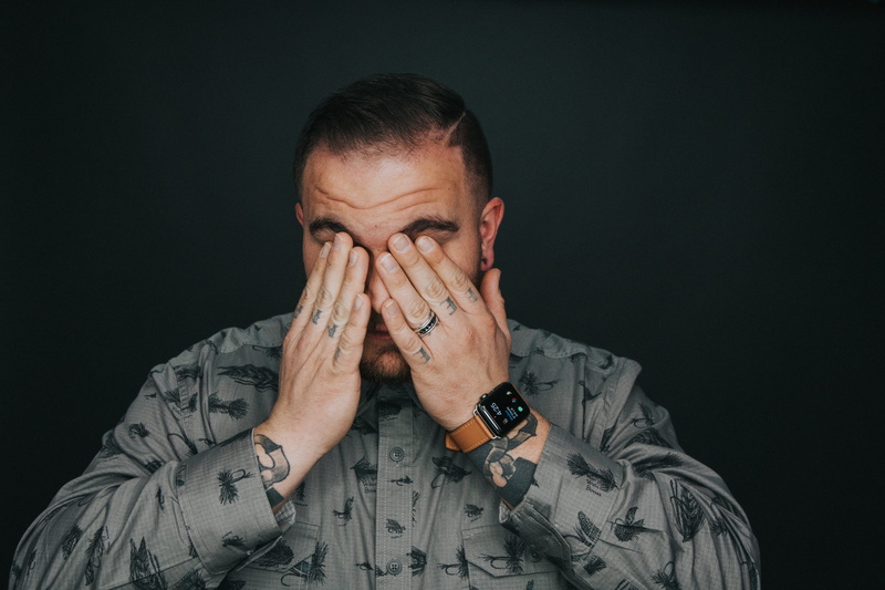 depression - sadness, human body part, tattoo, contemplation, tat, model, front view, eye, indoors, eyes, man, head in hands, studio, watch, body part