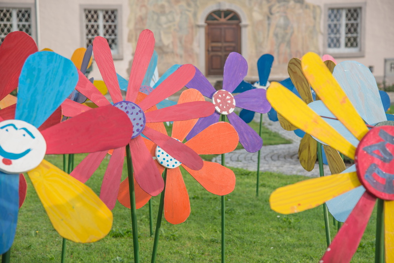 front yard, wooden flowers, flower, day, art, building exterior, yellow, large group of objects, 5K, no people, red, architecture, garden, multi colored