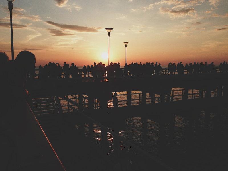 built structure, city, architecture, sun, dock, beach, beauty in nature, lifestyles, nature, orange color, cloud - sky, crowd, ocean, sunset, outdoors