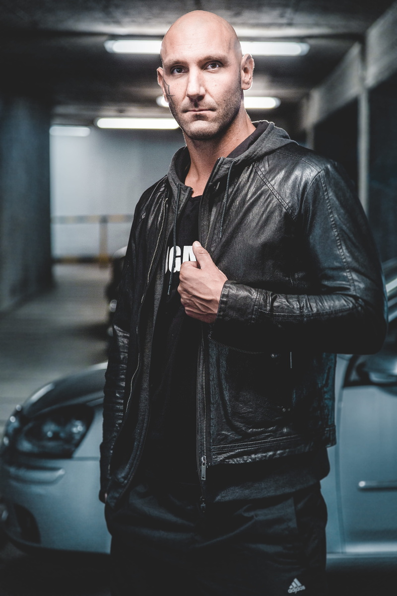 young, wearing, pose, vehicle, adult, looking at camera, mature men, 5K, car, photoshoot, black color, one person, leather, mid adult men, outerwear, clothing