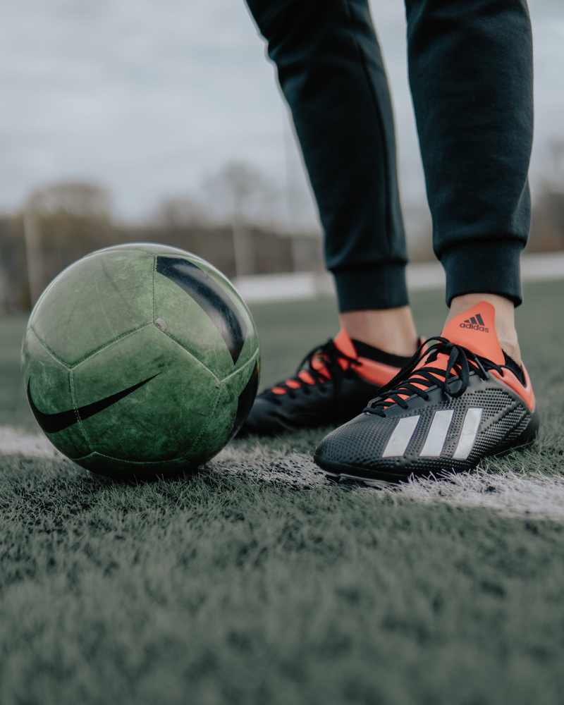 human foot, black, leather, human leg, body part, ball, standing, day, person, sports equipment, beside, outdoors, nike, sport, focus on foreground, low section