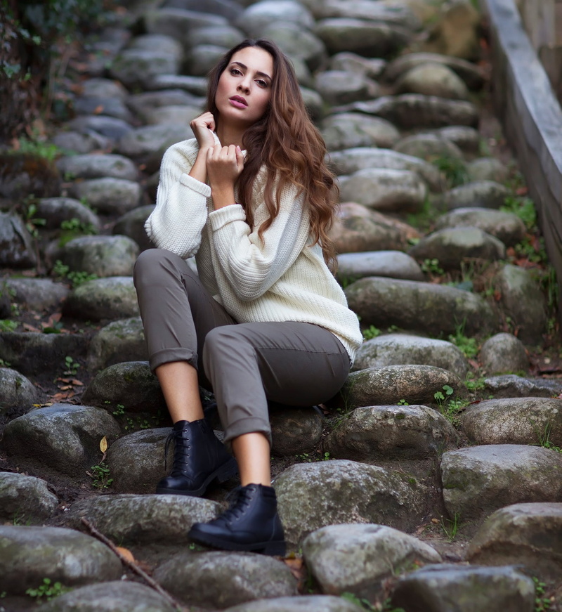 boots, lipstick, Joan Le Jan, 1080P, brunette, white clothing, sweater, makeup, outdoors, women, pants, looking at viewer, wavy hair, blush, stones, long