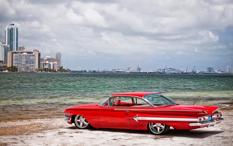 cityscape, day, skyscraper, land vehicle, city, office building exterior, outdoors, sea, motor vehicle, car, architecture, red, building, mode of transportation