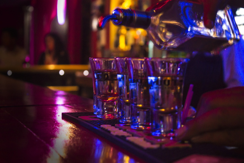 glasses, bar - drink establishment, pouring, shot glass, cocktail, happy hour, human hand, night, cups, clubbing, human body part, bar counter, drinking glass